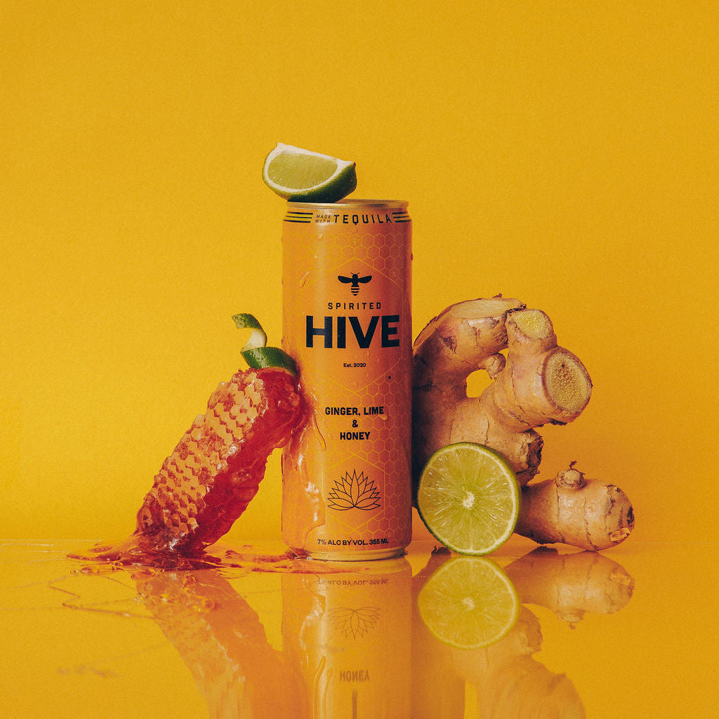 Can of 'The Hive' drink with pineapple, lime, and ginger on a yellow background